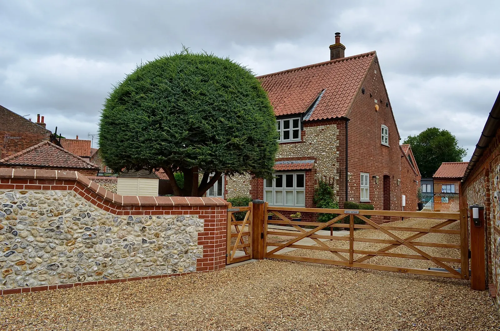 Gravel driveway and brick and flint wall in front of a house