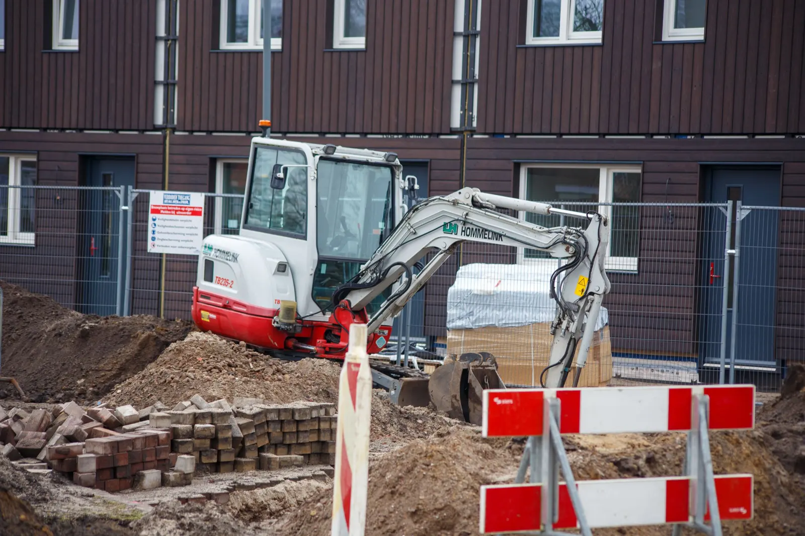 Mini digger working beside new-build homes